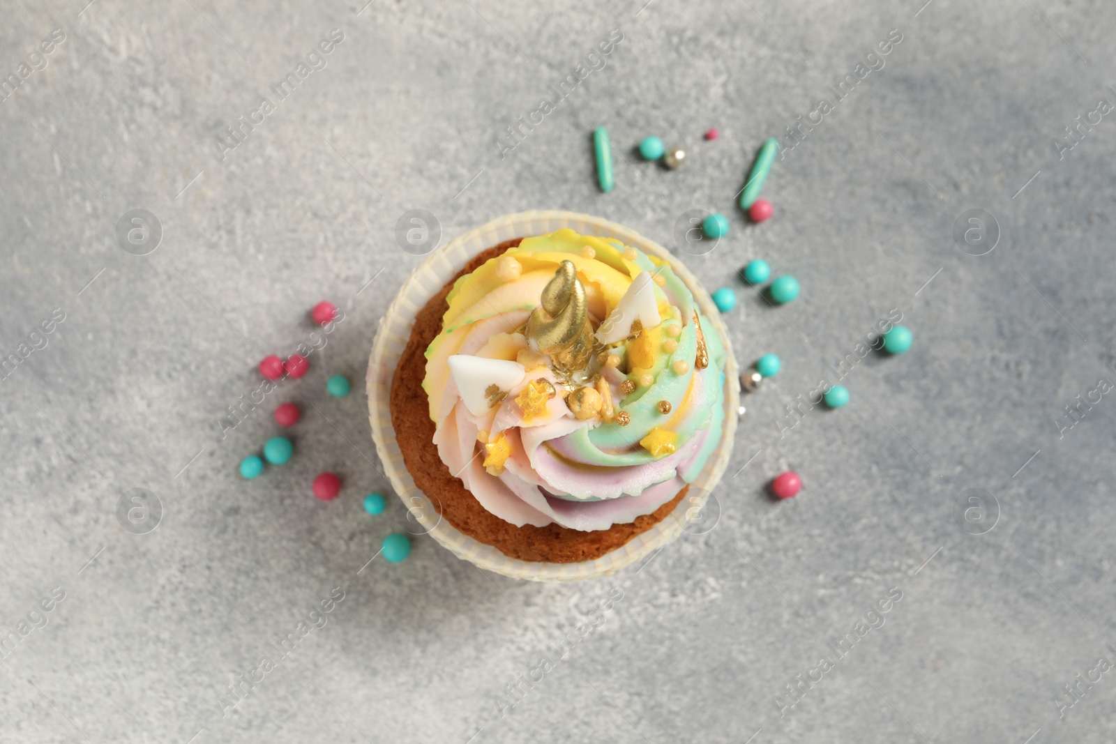 Photo of Cute sweet unicorn cupcake on light grey table, top view