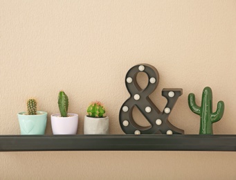 Photo of Shelf with beautiful cacti on color wall