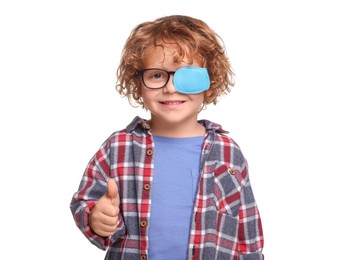 Photo of Happy boy with eye patch on glasses showing thumb up against white background. Strabismus treatment