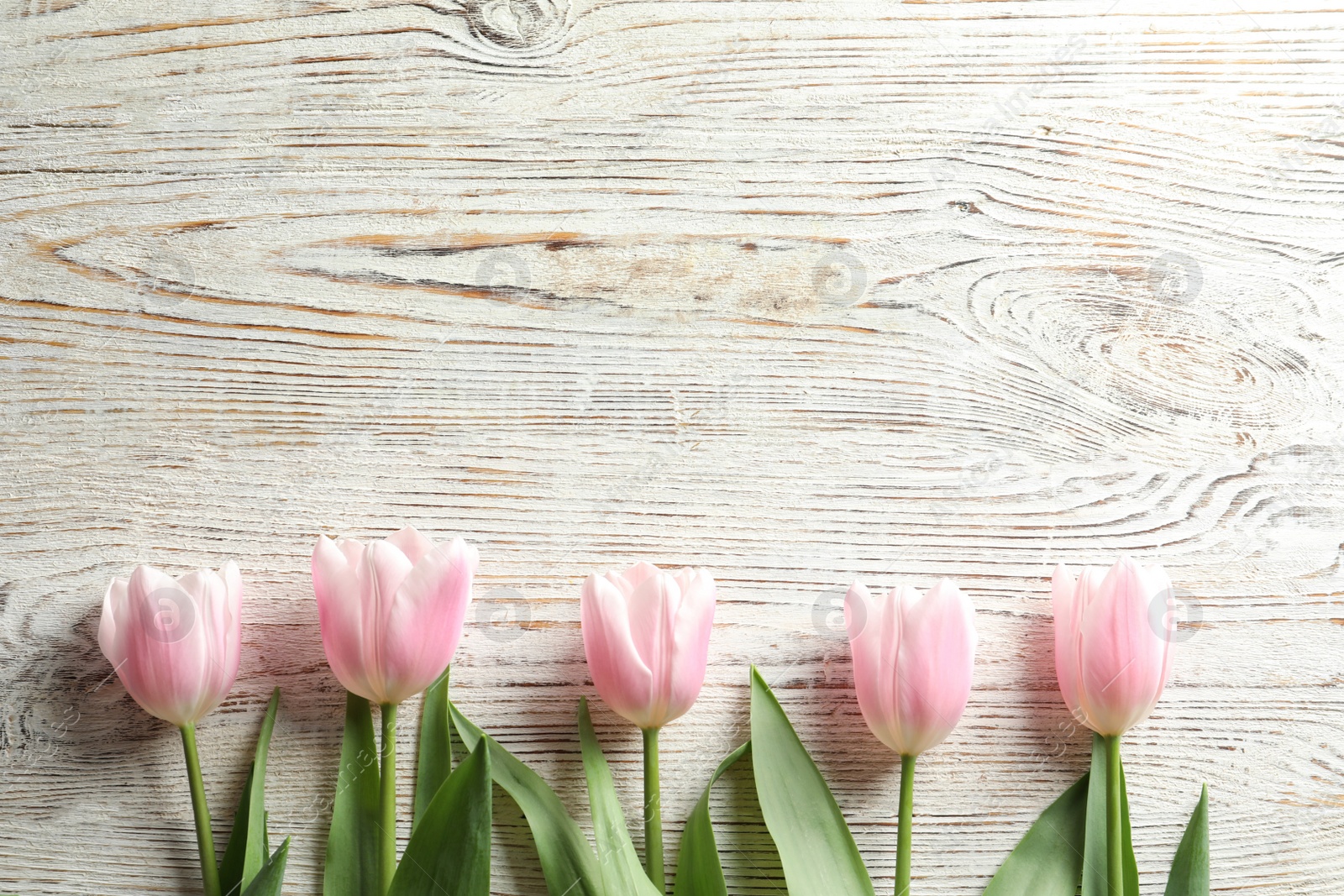 Photo of Beautiful tulips for Mother's Day on wooden background, top view