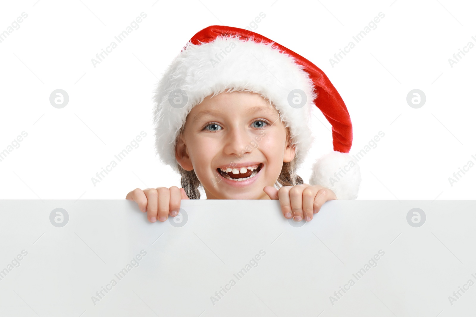 Photo of Happy child in Santa hat peeping out of blank banner on white background. Christmas celebration