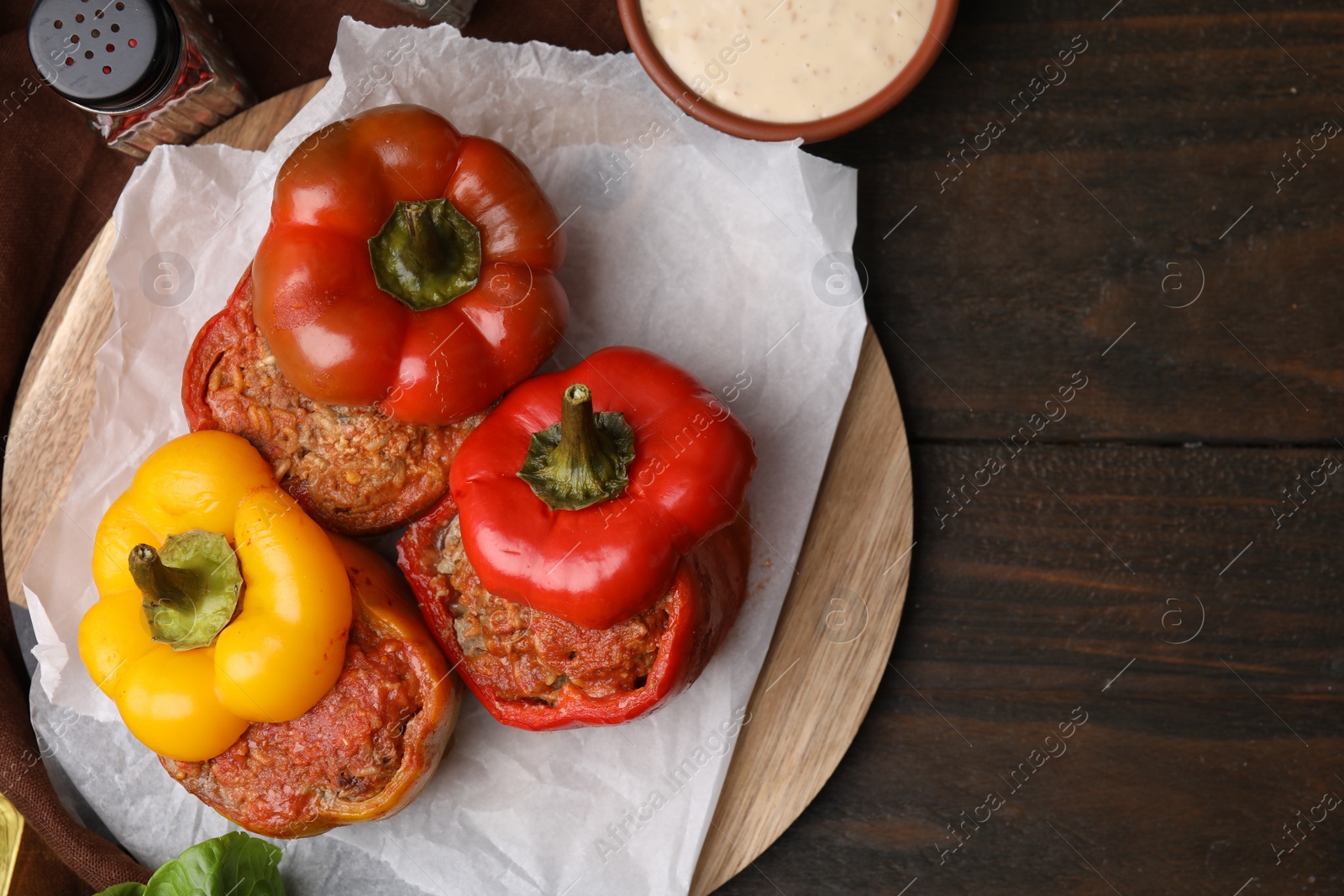 Photo of Delicious stuffed bell peppers served on wooden table, flat lay. Space for text