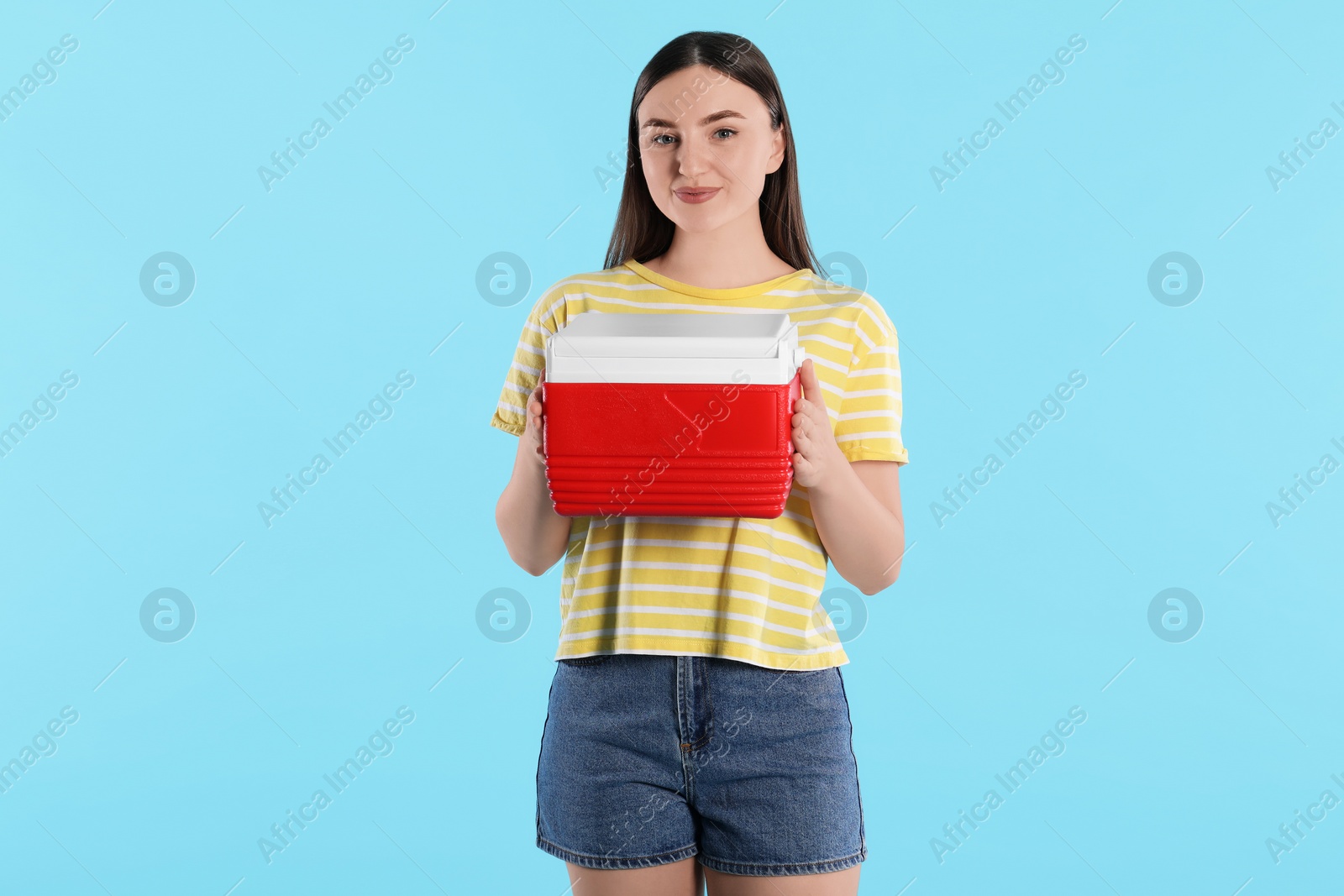 Photo of Beautiful young woman with plastic cool box on light blue background