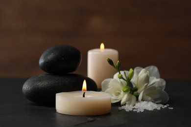 Photo of Beautiful composition with spa stones, burning candles and flowers on black table