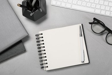 Photo of Flat lay composition with notebooks, keyboard and glasses on light grey table