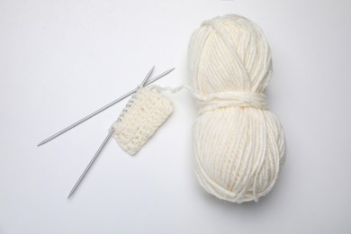 Photo of Soft woolen yarn, knitting and metal needles on white background, top view