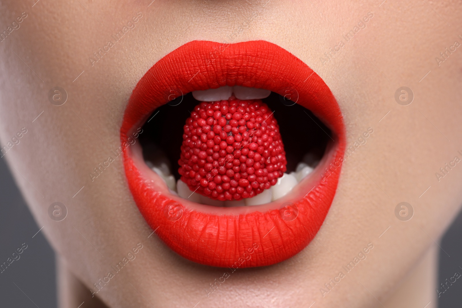 Photo of Beautiful young woman with red lips makeup eating candy, closeup