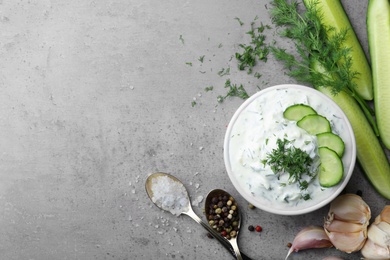 Photo of Cucumber sauce with ingredients on grey background, flat lay. Space for text