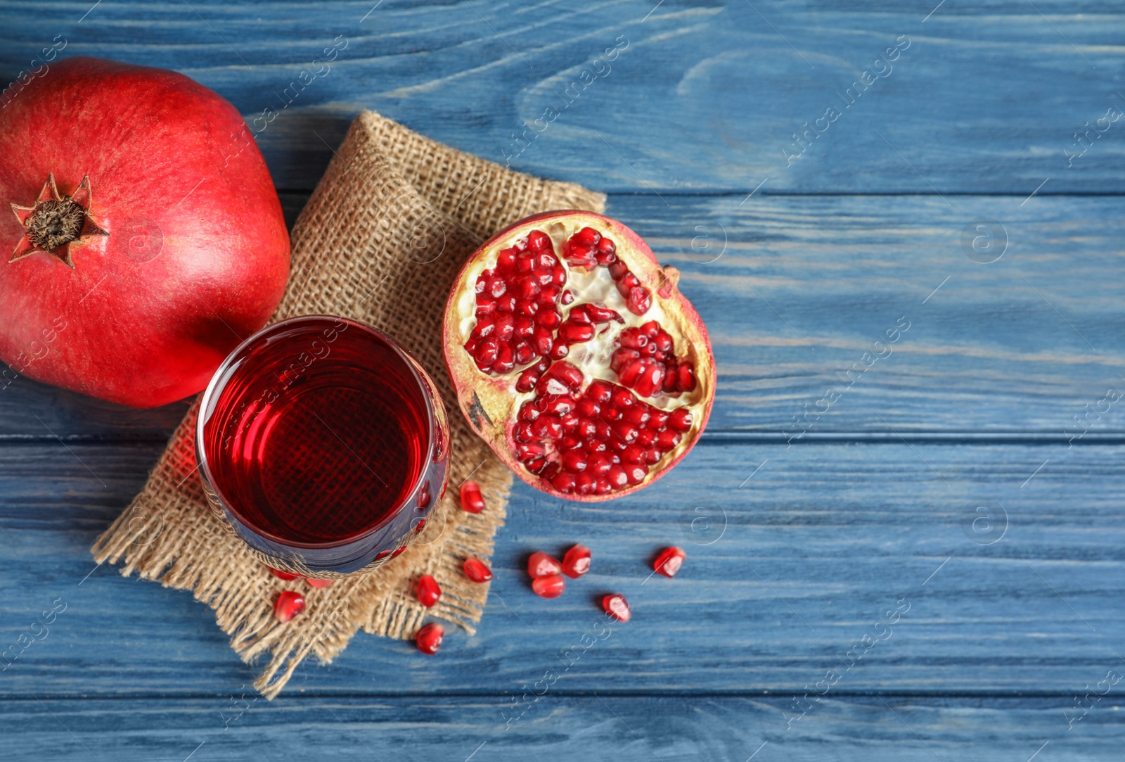 Photo of Glass of pomegranate juice and fresh fruits on wooden background, top view with space for text