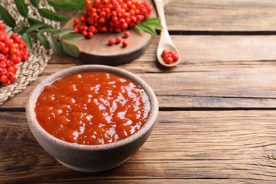 Photo of Delicious rowan jam in bowl on wooden table. Space for text