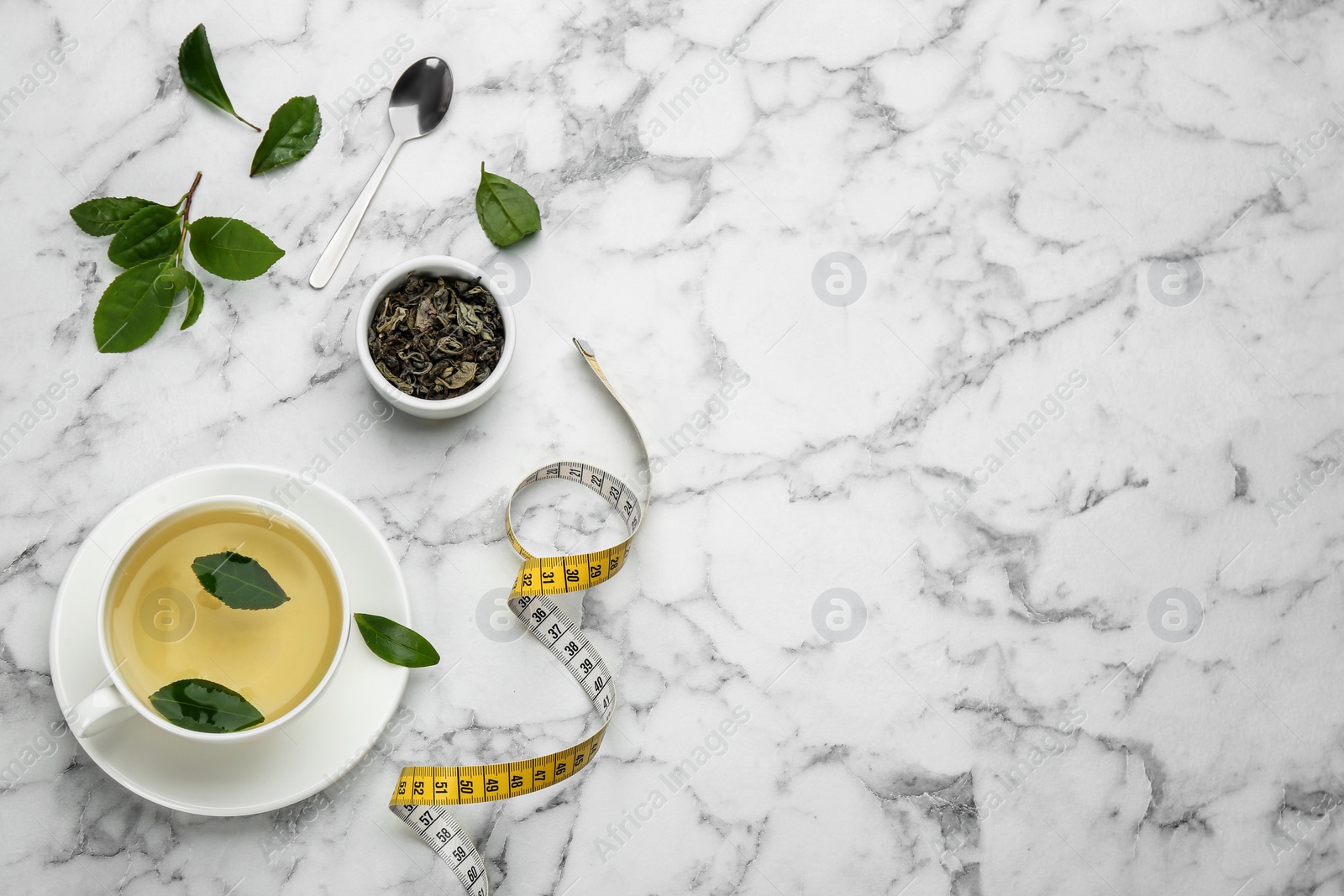 Photo of Flat lay composition with cup of diet herbal tea and measuring tape on white marble background, space for text