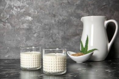 Photo of Glasses of hemp milk on grey table