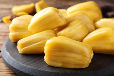 Photo of Delicious exotic jackfruit bulbs on wooden table, closeup