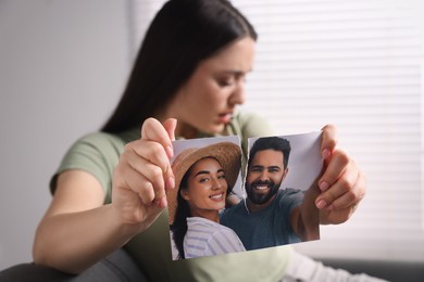 Photo of Upset woman ripping photo indoors, focus on picture. Divorce concept