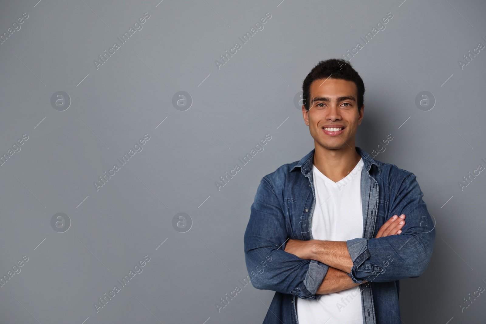 Photo of Handsome young African-American man on grey background. Space for text