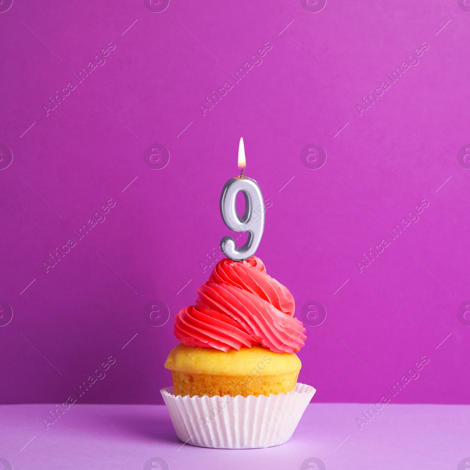 Photo of Birthday cupcake with number nine candle on violet background