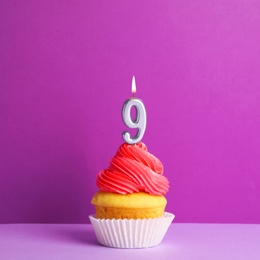 Birthday cupcake with number nine candle on violet background