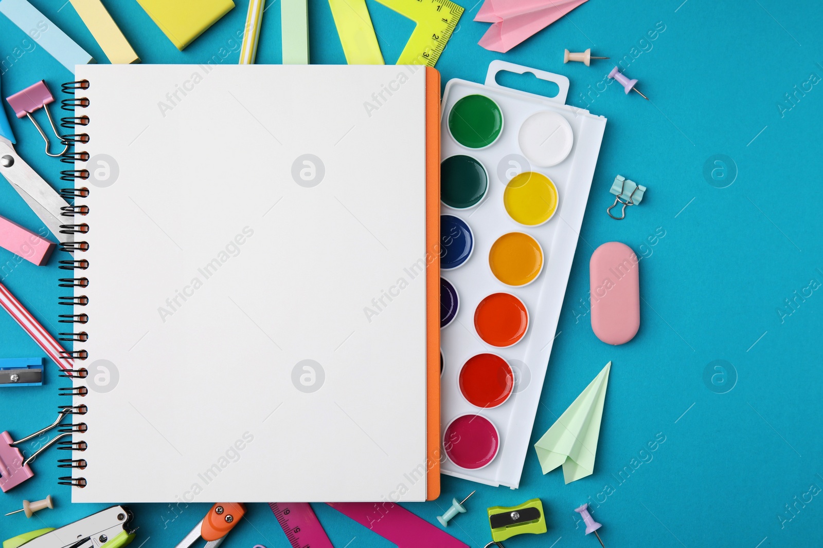 Photo of Different school stationery items and notebook on light blue background, flat lay with space for text. Back to school