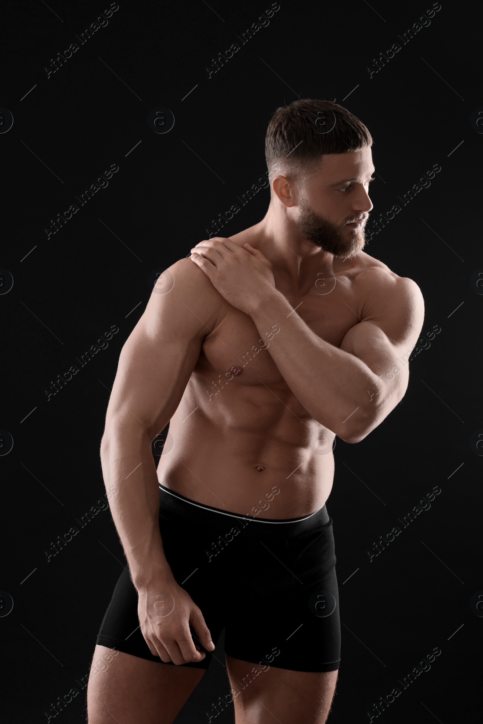 Photo of Young man in stylish underwear on black background