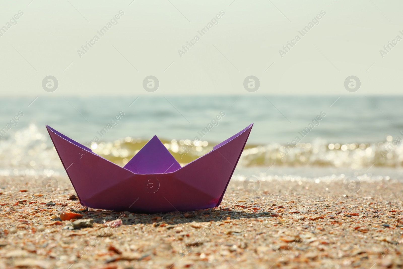 Photo of Purple paper boat near river on sunny day, space for text