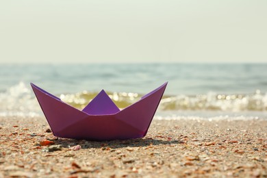 Photo of Purple paper boat near river on sunny day, space for text