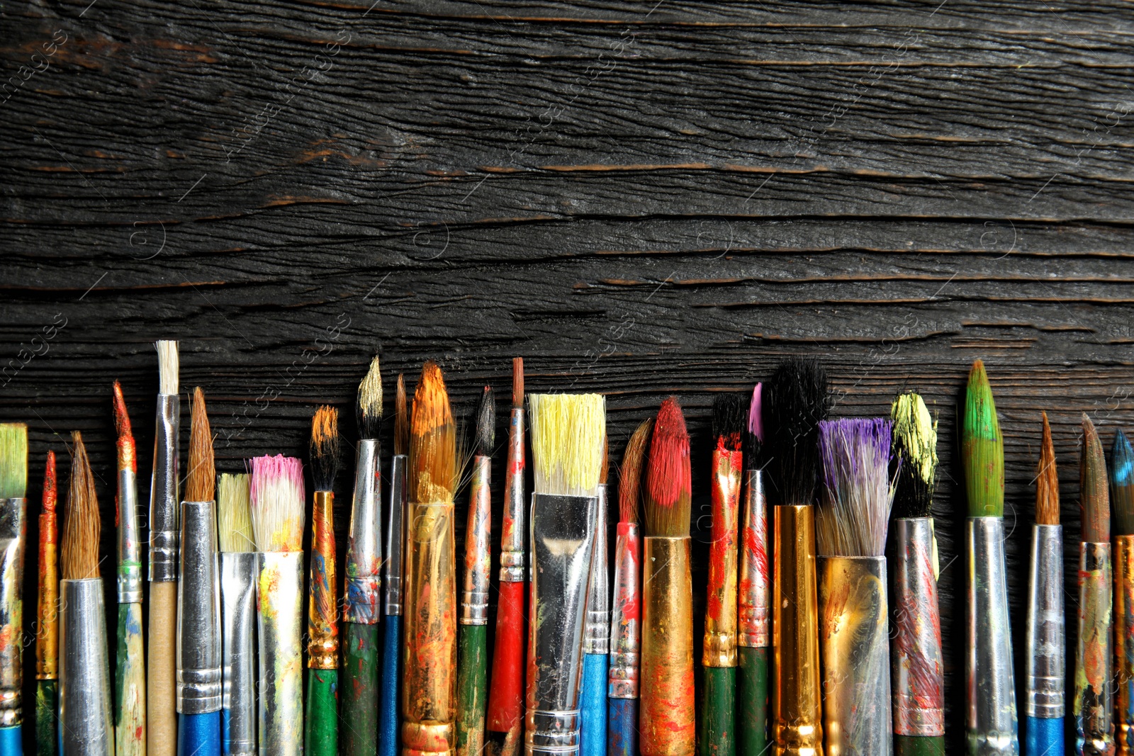 Photo of Different paint brushes on wooden background, top view with space for text