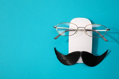 Photo of Artificial moustache, computer mouse and glasses on light blue background, top view. Space for text