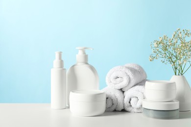 Different bath accessories and gypsophila on white table against light blue background