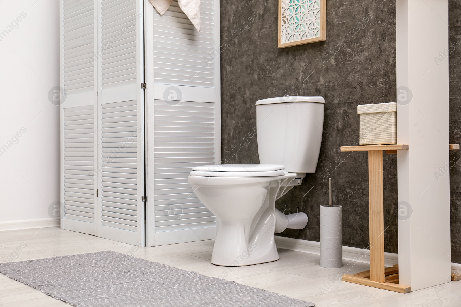 Photo of Toilet bowl near dark wall in modern bathroom interior