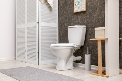 Photo of Toilet bowl near dark wall in modern bathroom interior