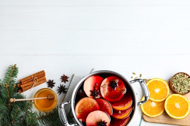 Photo of Delicious mulled wine and ingredients on white wooden table, flat lay. Space for text