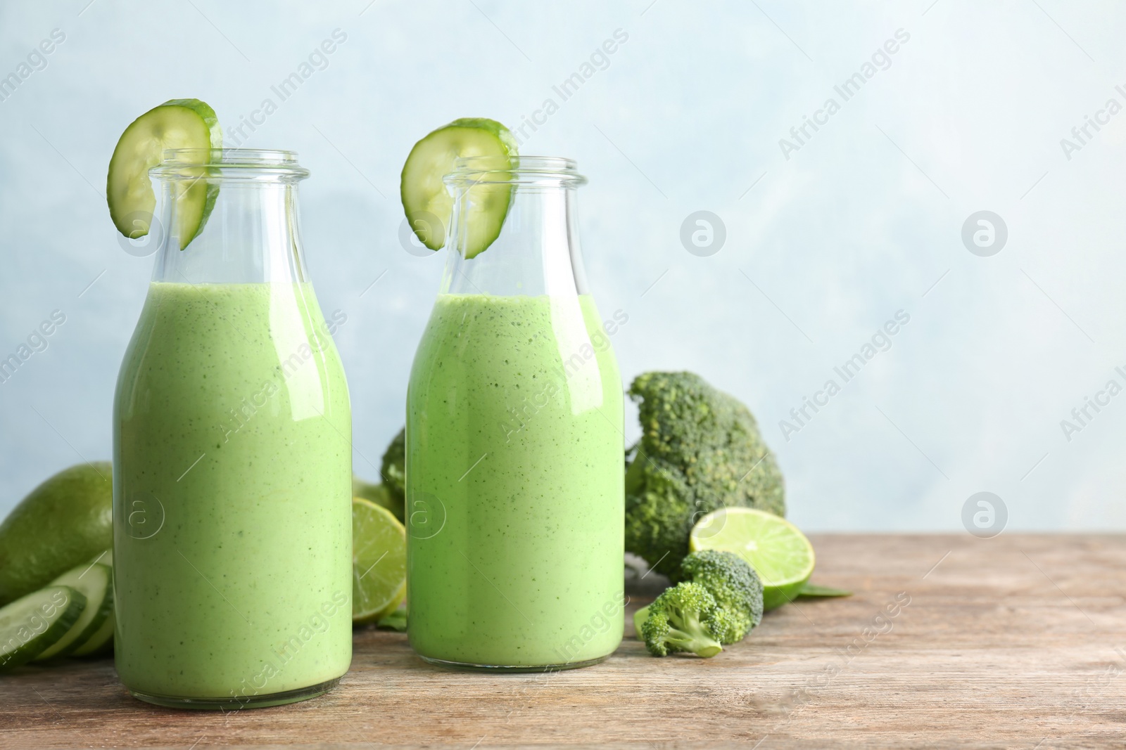 Photo of Bottles with healthy detox smoothie and ingredients on table