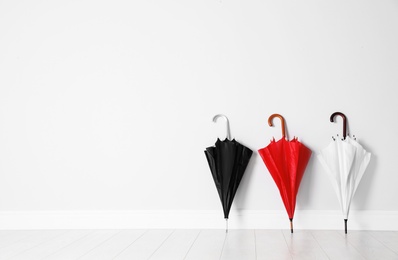 Photo of Beautiful bright umbrellas on floor near white wall with space for design