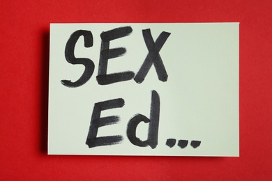 Photo of Piece of paper with text "SEX ED..." on red background, top view