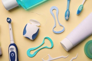 Flat lay composition with tongue cleaners and teeth care products on color background