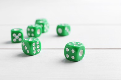 Photo of Many green game dices on white wooden table