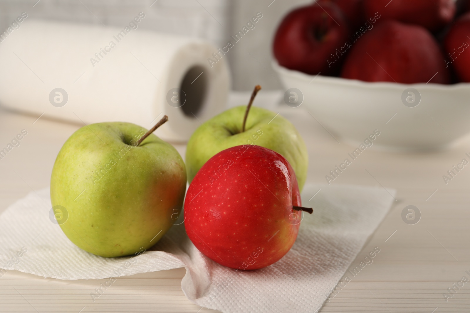 Photo of Fresh apples and paper towel on light wooden table, closeup