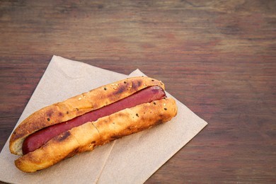 Fresh tasty hot dog on wooden table. Space for text