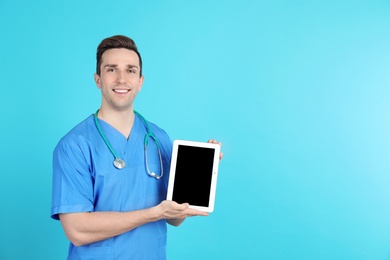 Photo of Portrait of medical assistant with stethoscope and tablet on color background. Space for text