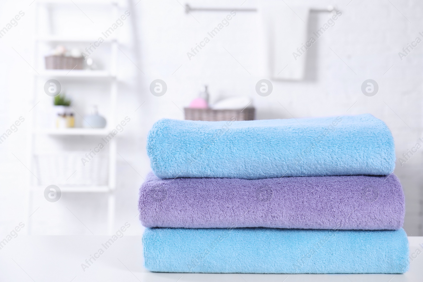 Photo of Stack of fresh towels on table in bathroom. Space for text