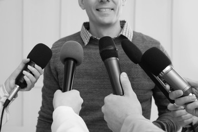 Image of Man giving interview to journalists indoors, closeup. Black and white effect