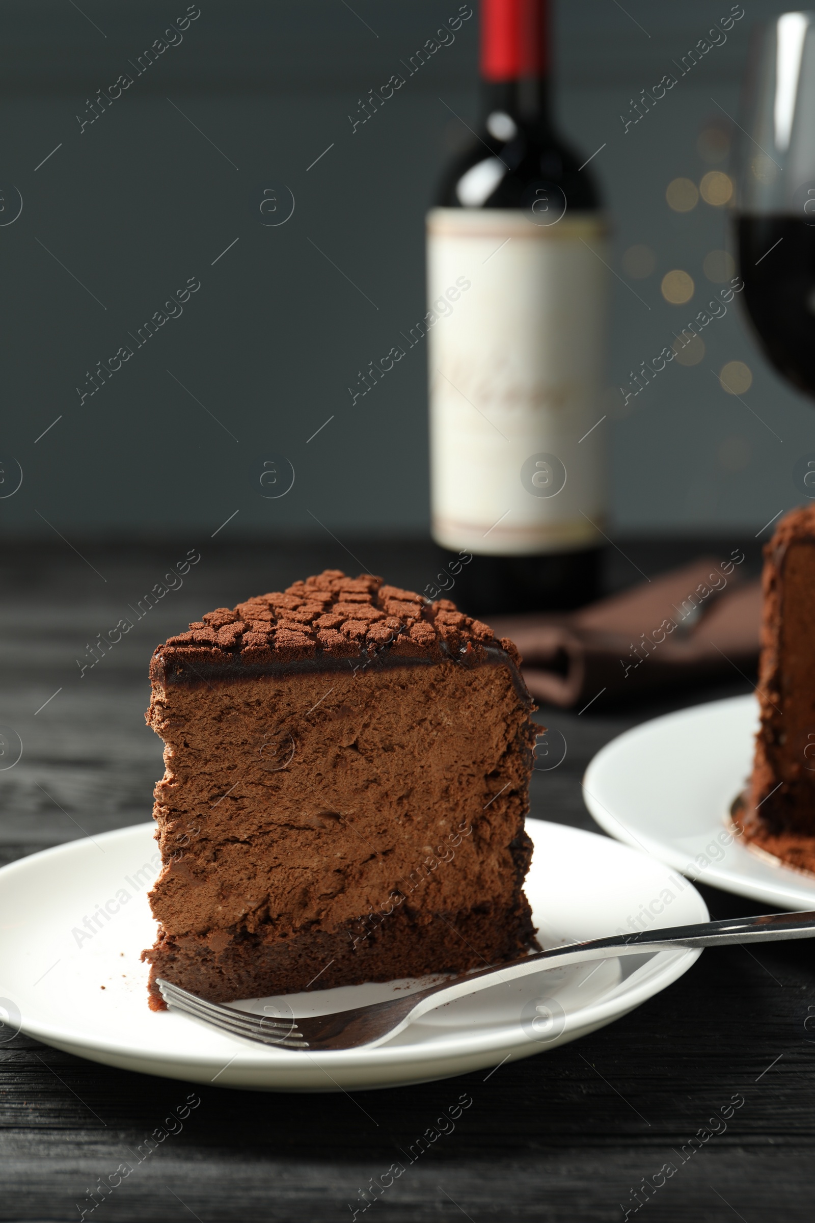 Photo of Piece of delicious chocolate truffle cake and fork on black wooden table