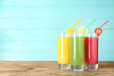 Photo of Three glasses of different juices with straws on table. Space for text