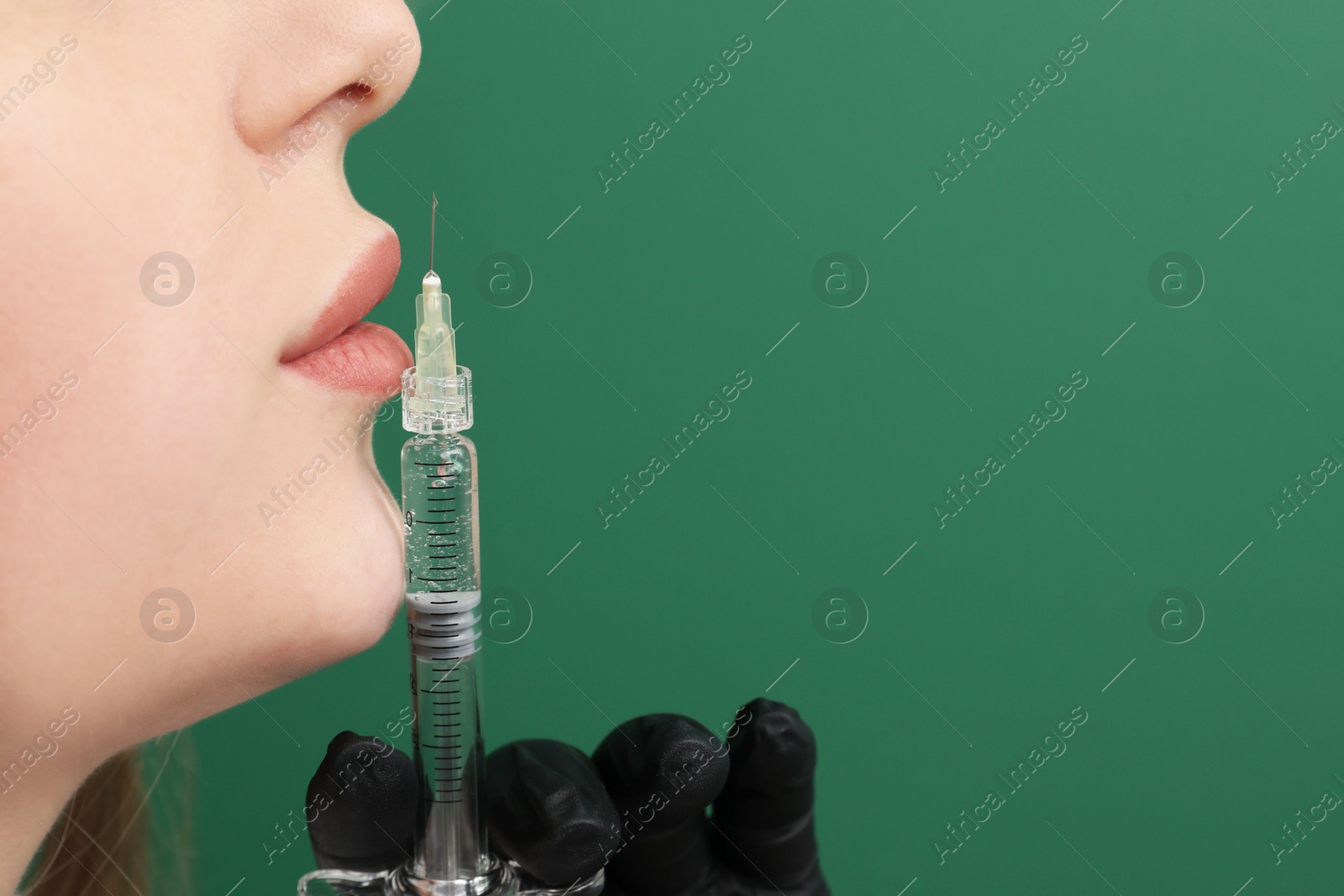 Photo of Cosmetologist with syringe on green background, closeup. Space for text