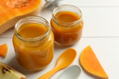 Photo of Tasty baby food in jars and ingredients on white table, closeup