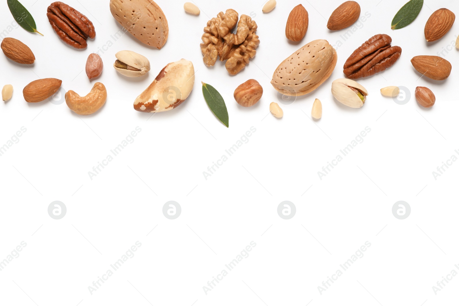 Photo of Different nuts and leaves on white background, flat lay. Space for text