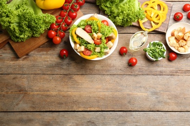 Delicious chicken salad and fresh vegetables on wooden table, flat lay. Space for text