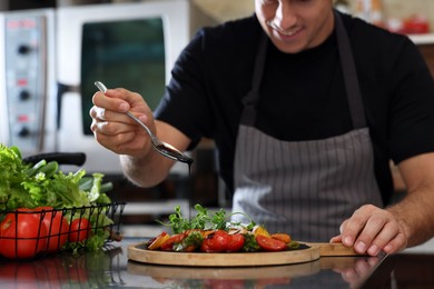 Photo of Professional chef decorating cooked dish with sauce in restaurant kitchen, closeup