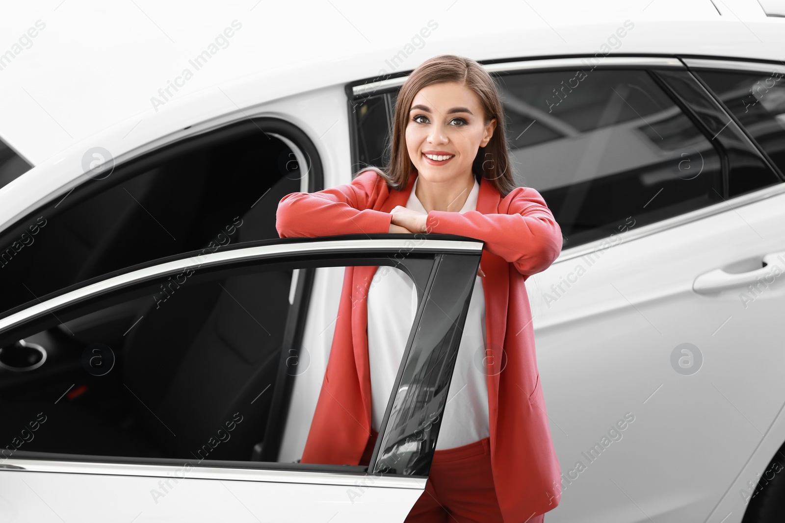 Photo of Young woman standing near new car in salon