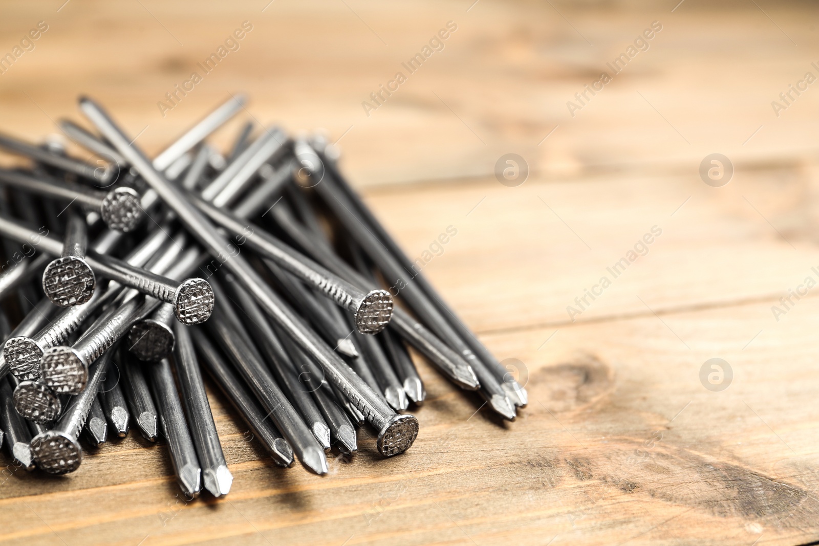 Photo of Pile of metal nails on wooden background, closeup. Space for text